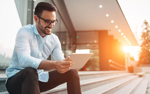 Man sitting on steps looking at a tablet